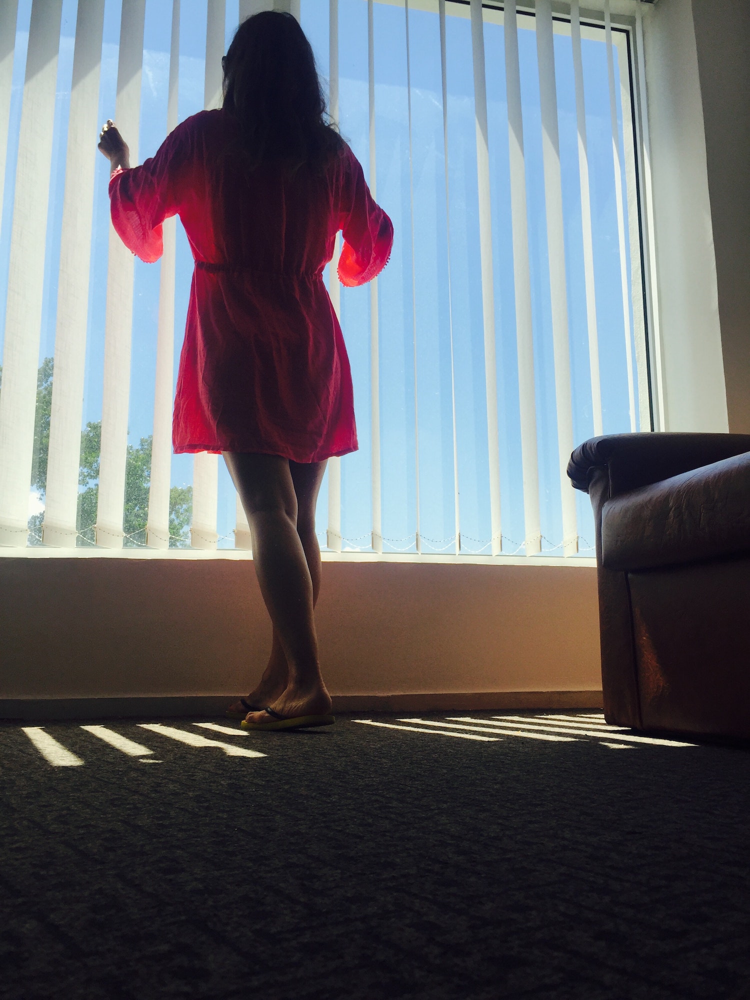 Woman standing near the window blinds